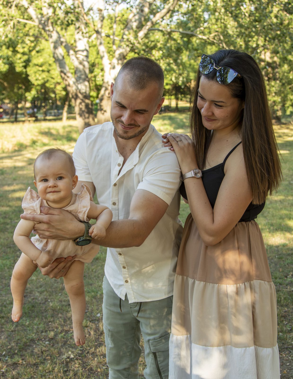 Édesapa karjában a kisbaba, édesanya mosolyog