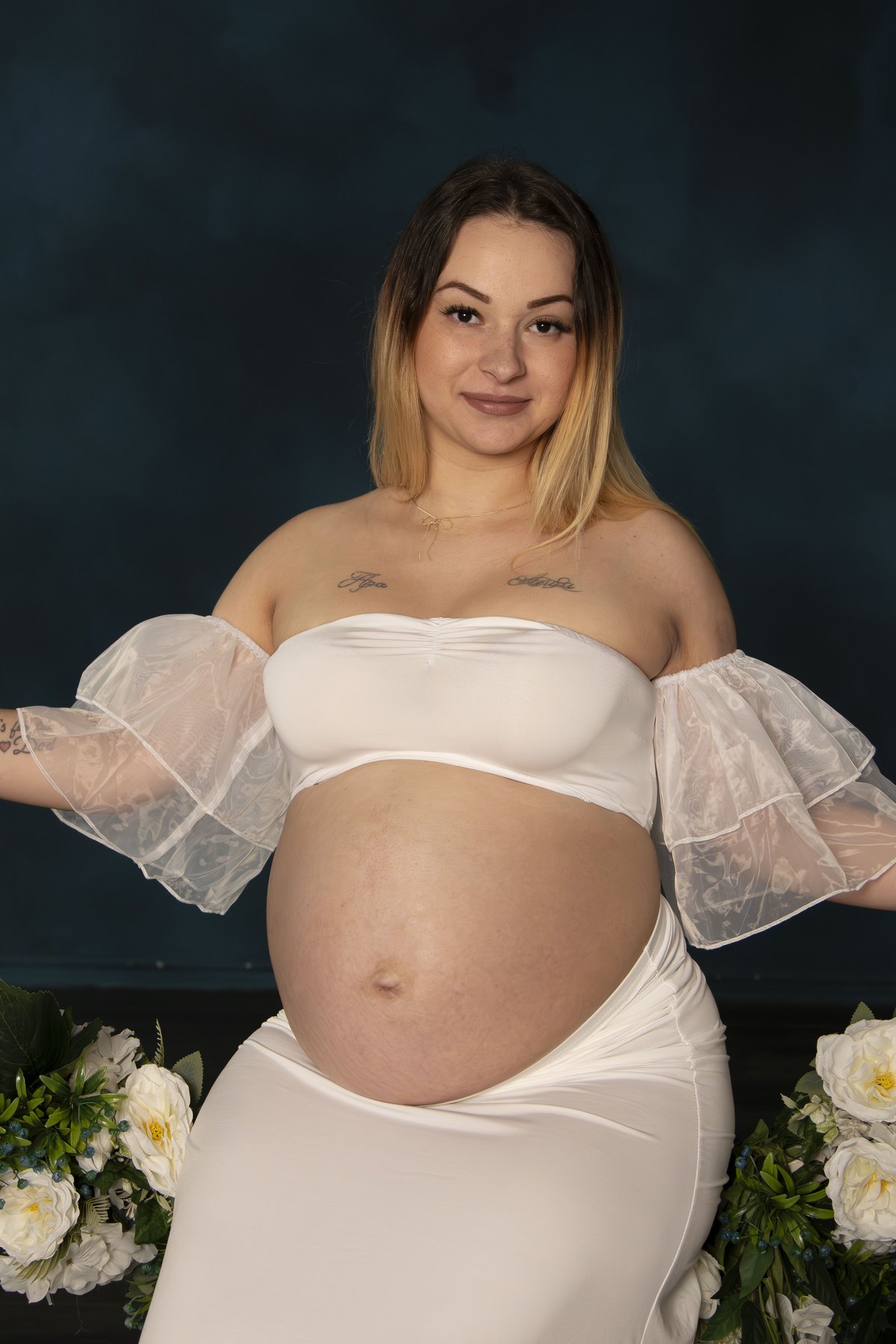Kismama fehér ruhában csokorral